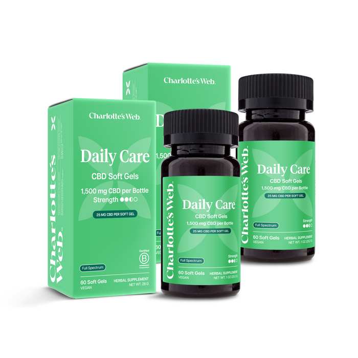 Two bottles and two boxes of Charlotte's Web Daily Care CBD Soft Gels on a white background